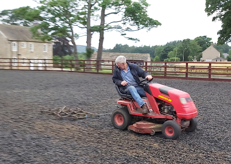 man on a mini tractor harrowing an arena